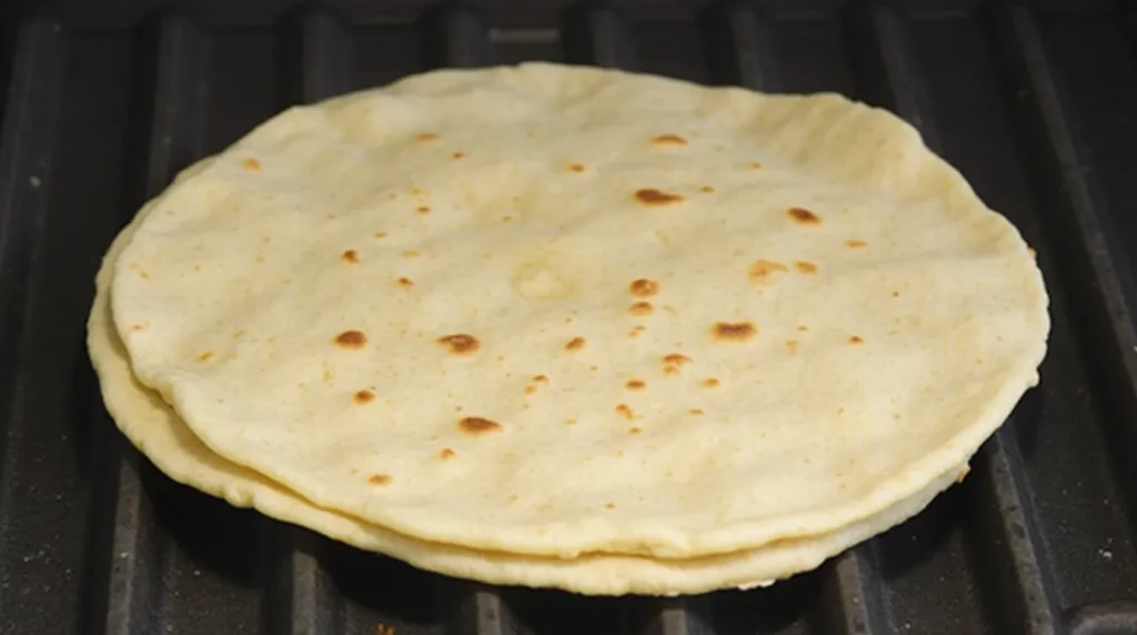 Freshly cooked tortillas stacked on a grill pan.